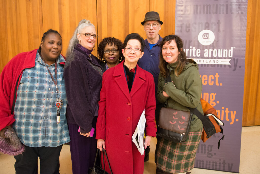 Six people stand in front of a Write Around Portland banner.