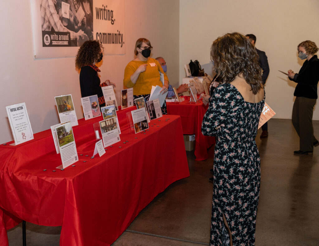 People stand in front of tables at our annual auction.